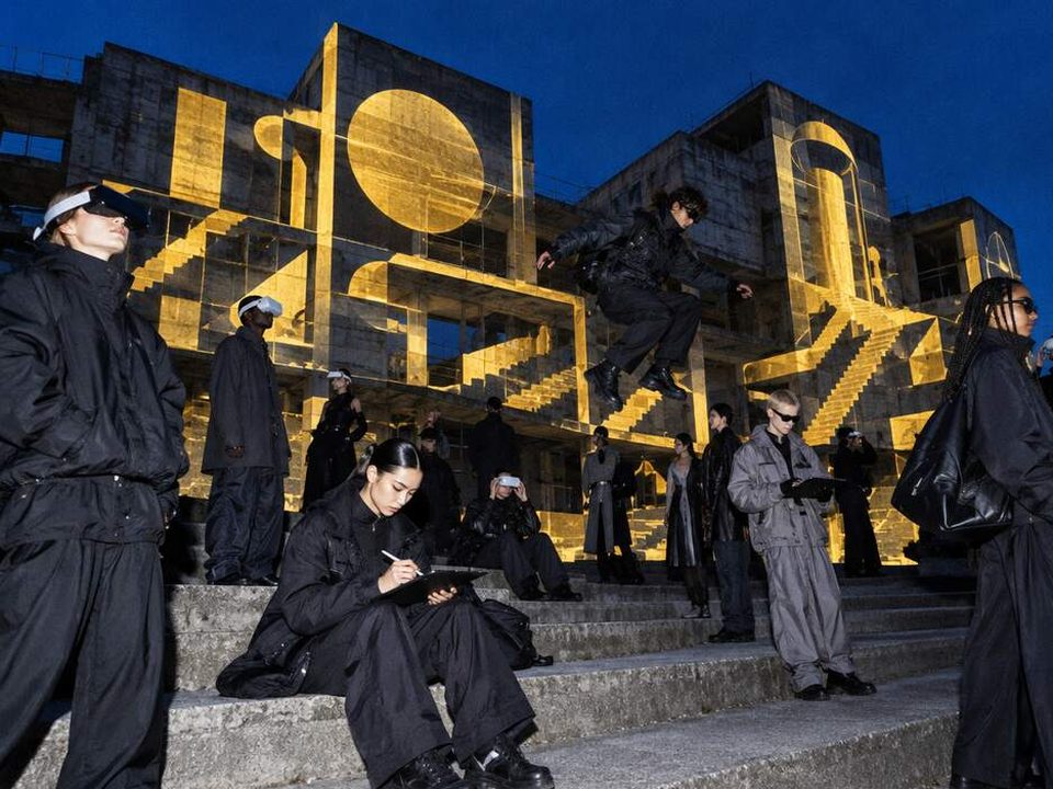 Young creators with VR headsets and tablets on concrete steps at blue hour, golden ideas projected onto the facade of an abandoned building, one mid-jump